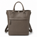 Front view of taupe leather tote bag with handles and straps.