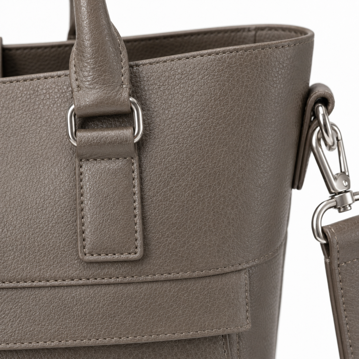 Snap closure detail on the taupe leather tote bag.